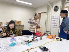 高橋さん（右端）の助言を受けながらおもちゃを“診察”する富士田さん（中央）ら