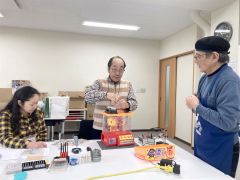 高橋さん（右端）の助言を受けながらおもちゃを“診察”する富士田さん（中央）ら