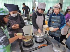 炊いたご飯やみそ汁を盛り付ける児童たち