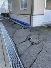 避難所となっている宇ノ気小学校の体育館裏。コンクリートが割れている