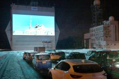 格納庫シャッターに投影された映像を車中から鑑賞する来場者（７日、金野和彦撮影）