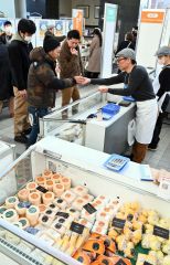 販売員の説明を受けながらチーズを試食する来場者（１２日午前１０時５０分ごろ、とかちプラザ特設会場で。金野和彦撮影）