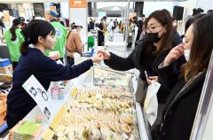 販売員の説明を受けながらチーズを試食する来場者（１２日午前１０時半ごろ、とかちプラザ特設会場で。金野和彦撮影）
