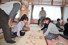 下の句歌留多に挑戦する子どもら（左が島田会長、同４人目が大熊さん）