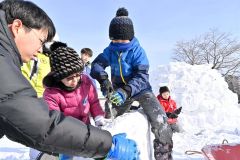 雪のブロックを成形する参加者たち