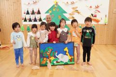篠原学級長（後列中央）から組み木パズルを受け取った上更別幼稚園の園児たち（村提供）