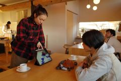 タブレットを使い、北海道や十勝をイメージしたＴシャツについて説明する岩松このみさん（左）