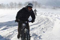 風が強く雪が舞う中で雪上ファットバイクを体験する参加者