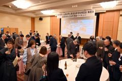 高校の歴史が紹介される映像が流れる会場で歓談する卒業生ら