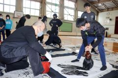 ジャンボ書道に挑戦する児童と八重樫さん（左）