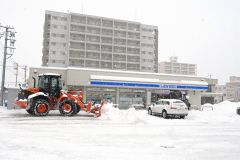 来店客の車に注意を払いながら作業する除雪ドーザー（２３日午前９時ごろ。帯広市内のコンビニエンスストア前
）
