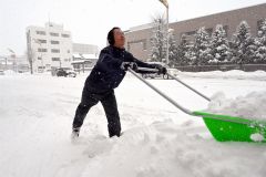 早朝から除雪作業に追われる市民ら（２３日午前９時ごろ。柳月大通本店前で）