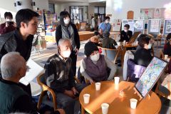 沖縄の伝統的な染め物「紅型」のデザインを村民と鑑賞する前田さん（左）
