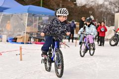 子ども用のマウンテンバイクに乗って雪上を走る子どもたち（２８日午前１０時半ごろ。金野和彦撮影）
