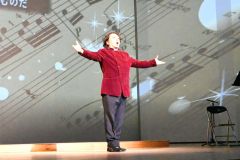 プロジェクションマッピングを映し出した舞台で歌声を響かせる原田さん