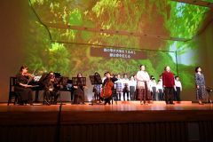 ステージで本多静六の人生を名曲と朗読、映像で表現した。前列右から２人目が原田さん