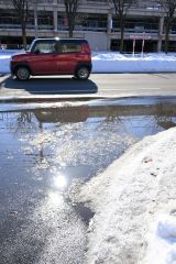 気温が上がり、車道に水たまりができた（３０日正午ごろ。市内西６南１９で。金野和彦撮影）
