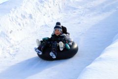 ゴムチューブで雪の滑り台を滑走し、歓声を上げる子どもたち