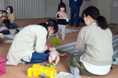 乳幼児の人形で胸骨圧迫を体験する保護者