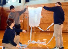 内山さん（左から２人目）と手作りの熱気球を飛ばしてみる児童と教員ら