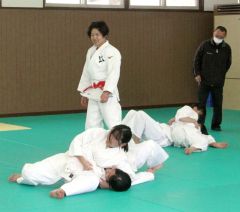 中村さん（左）からけさ固めを教わる勇足中の生徒たち