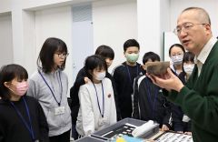 倉橋さん（右）から道埋蔵文化財センター所有の先史・古代の石器について解説してもらう児童ら