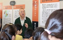 ふるさと資料館に展示している先史時代の石器などについて解説する倉橋さん（中央）