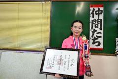 出展作品「仲間たち」の前でトロフィーと賞状を手にする葛葉さん