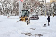 除雪に追われる帯広日産ドーム店の従業員（１６日、午前９時ごろ、市内西７南２０で。金野和彦撮影）