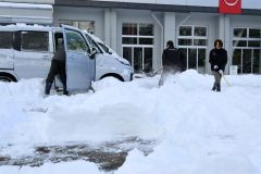 除雪に追われる帯広日産ドーム店の従業員（１６日、午前９時ごろ、市内西７南２０で。金野和彦撮影）