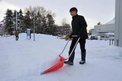 除雪に追われる帯広日産ドーム店の従業員（１６日、午前９時ごろ、市内西７南２０で。金野和彦撮影）