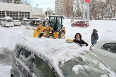 除雪作業に追われる従業員（１６日、午前９時ごろ、市内西７南２０、日産ドーム店で。金野和彦撮影）