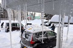 つららが垂れ下がる中、除雪作業に追われる従業員（１６日、午前９時ごろ、市内西７南２０、日産ドーム店で。金野和彦撮影）
