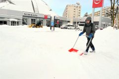 除雪に追われる帯広日産ドーム店の従業員（１６日、午前９時ごろ、市内西７南２０で。金野和彦撮影）