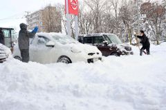 除雪に追われる帯広日産ドーム店の従業員（１６日、午前９時ごろ、市内西７南２０で。金野和彦撮影）