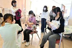 赤ちゃんの抱き方や授乳体験をする子ども（１７日、午前１１時４０分ごろ、金野和彦撮影）
