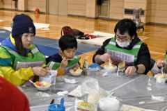 夕食としての炊き出しの“鳥ジャガ”を食べる参加者ら（１７日午後６時４５分ごろ、下音更中体育館）
