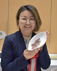 「白カビ付きサラミソーセージ」を手にする大美浪店長
