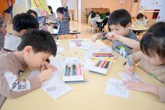 商品が描かれた塗り絵を丁寧に塗る園児ら