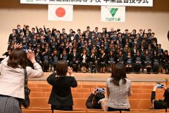 写真を写す保護者らに向けポーズを取る卒業生ら