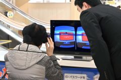 ゴーグルを付けてＶＲ体験をする参加者と解説する警察官（右）