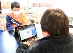 パソコンを使ってプログラミングを行う児童ら