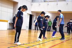 小西康道監督（右）からトレーニングを通じて体の動かし方を学ぶ団員たち