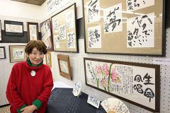 小池さんの作品の横で笑顔を見せる有田さん