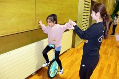 一輪車教室で初心者の補助を行うクラブのメンバー