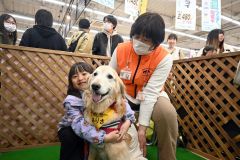 セラピードッグ「ありさ」との触れ合いを楽しむイベント来場者。写真右が岡本さん