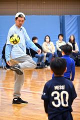 曽田会長（左）に教わりながらサッカーをする児童たち