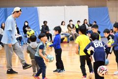 曽田会長（左）に教わりながらサッカーをする児童たち
