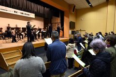 陸上自衛隊第５音楽隊の演奏で「花は咲く」を合唱する来場者