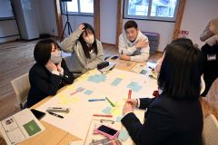 講師の今村さん（奥）とコミュニティナースの普及に関するアイデアを話し合う生徒たち
